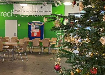 Geschmückter Weihnachtsbaum, Banner und Ausschnitt Stellwand. Aufnahmen Brecht-Schule